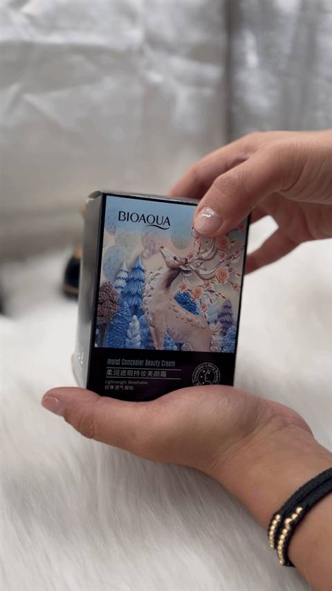 Manos sacando el compacto negro y dorado de su caja ilustrada y abriéndolo
